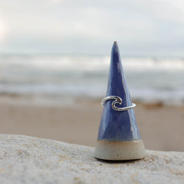 Blue ceramic cone with a silver wave ring on a beach