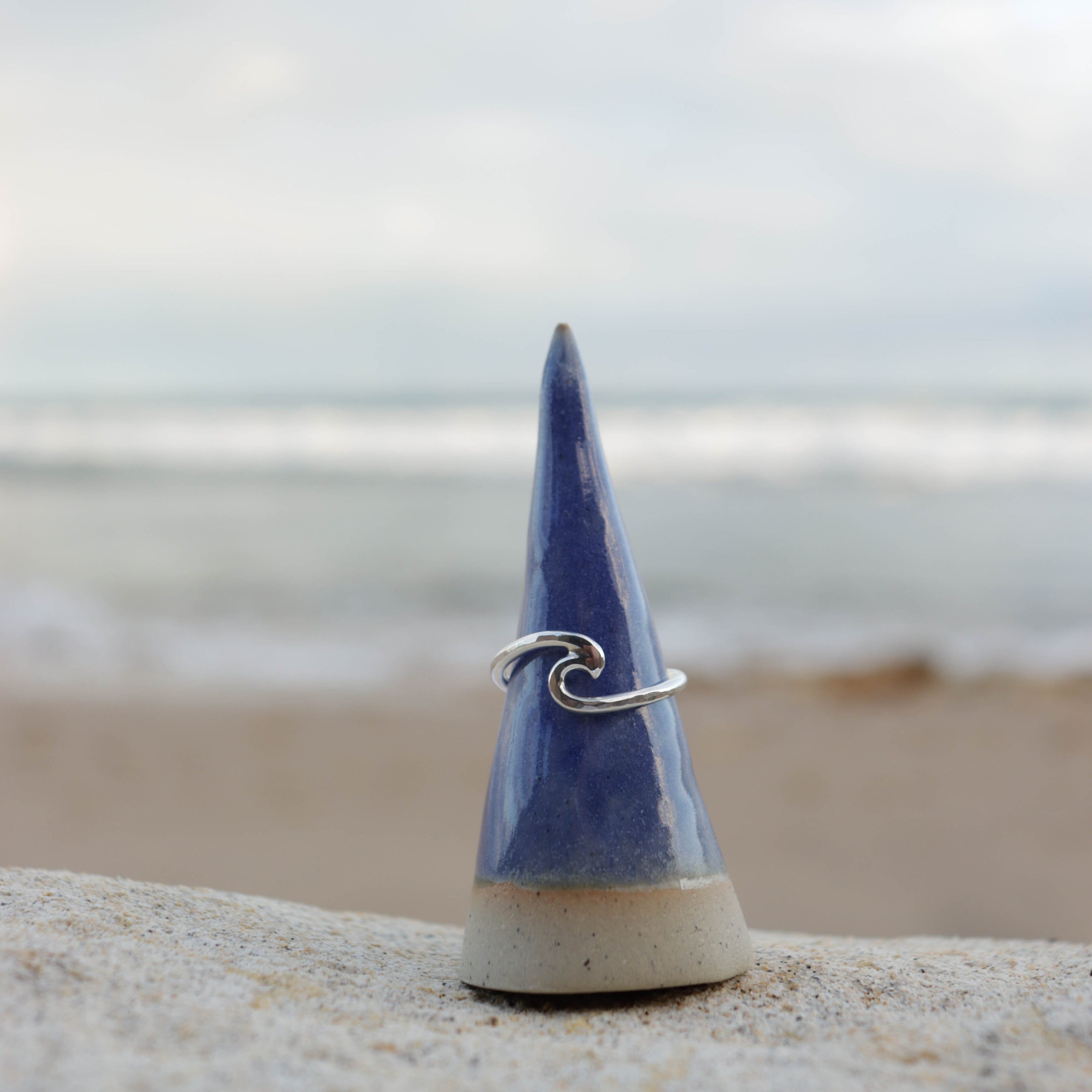 Blue ceramic cone with a silver wave ring beach in background